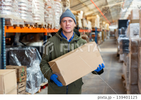 Fulfillment center worker standing and holding carboard box Fulfillment center worker standing and holding carboard box 139401125