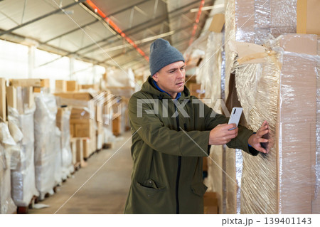 Storekeeper using his phone to take photograph of pasteboard box Storekeeper using his phone to take photograph of pasteboard box 139401143