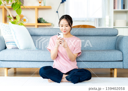 部屋でスマホを操作する若い女性 139402058
