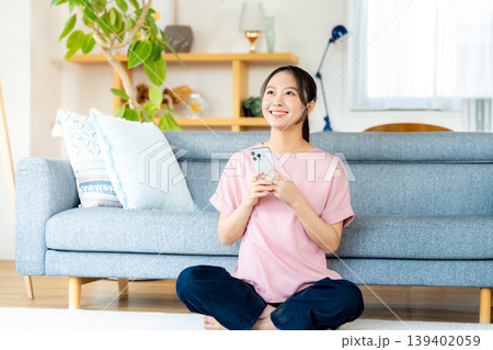 部屋でスマホを操作する若い女性 139402059