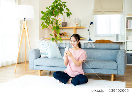 部屋でスマホを操作する若い女性 139402066