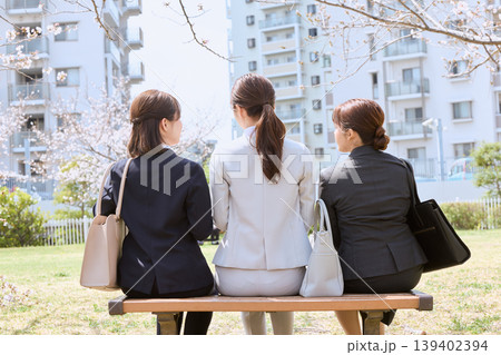 春の公園のベンチに座る3人のリクルートスーツ姿の女性・就職活動中の大学生の後ろ姿と桜 春の公園のベンチに座る3人のリクルートスーツ姿の女性・就職活動中の大学生の後ろ姿と桜 139402394