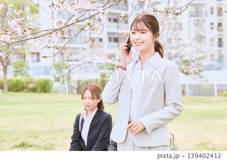 桜の下でスマートフォンで電話するスーツ姿の若い女性ビジネスパーソン・春の公園で働くOL 桜の下でスマートフォンで電話するスーツ姿の若い女性ビジネスパーソン・春の公園で働くOL 139402412