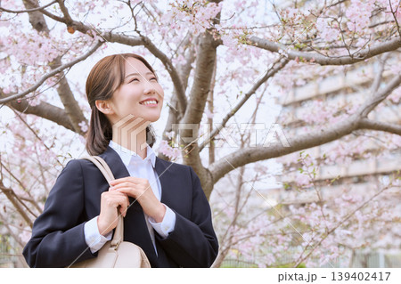 桜の下で微笑むリクルートスーツ姿の若い女性・春の新生活と就職活動イメージ 桜の下で微笑むリクルートスーツ姿の若い女性・春の新生活と就職活動イメージ 139402417
