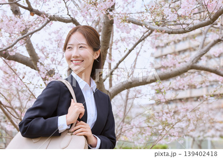 桜の下で微笑むリクルートスーツ姿の若い女性・春の就職活動・新社会人イメージ 桜の下で微笑むリクルートスーツ姿の若い女性・春の就職活動・新社会人イメージ 139402418