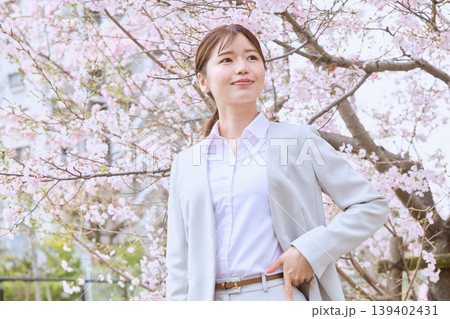桜の下で微笑む白スーツ姿の若い女性ビジネスパーソン・春の新生活イメージ 桜の下で微笑む白スーツ姿の若い女性ビジネスパーソン・春の新生活イメージ 139402431