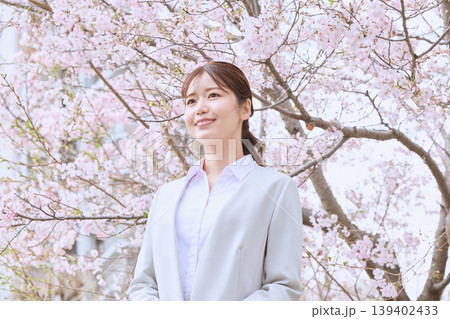 桜の下で微笑む若い女性ビジネスパーソン・春の新生活とキャリアのイメージ・スーツ姿の新入社員 桜の下で微笑む若い女性ビジネスパーソン・春の新生活とキャリアのイメージ・スーツ姿の新入社員 139402433