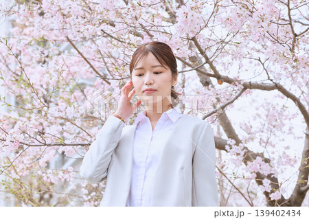 満開の桜の下に立つスーツ姿の若い女性・春の新生活イメージ・新入社員・就職活動 139402434