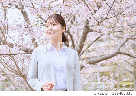 桜の下で微笑む若い女性・スーツ姿の新入社員が春の門出を迎えるイメージ 139402436