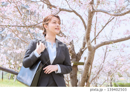 桜の下を歩く新入社員のリクルートスーツ姿の若い女性・春の就職活動イメージ 139402503