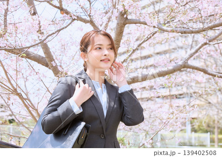 桜の下を歩くリクルートスーツ姿の若い女性・春の就職活動イメージ 桜の下を歩くリクルートスーツ姿の若い女性・春の就職活動イメージ 139402508