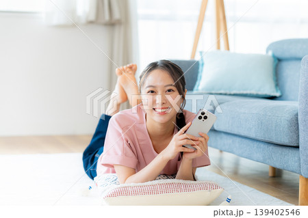 部屋でスマホを操作する若い女性 139402546