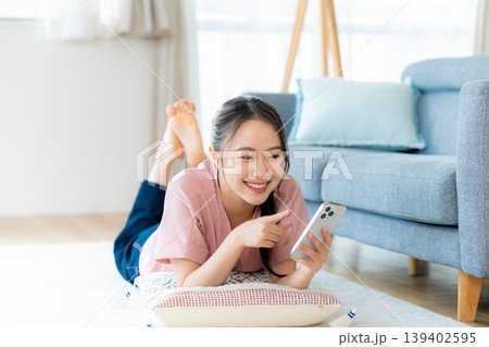 部屋でスマホを操作する若い女性 139402595