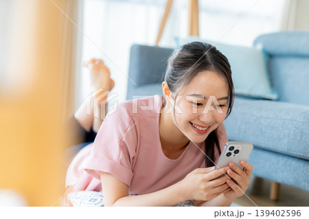 部屋でスマホを操作する若い女性 139402596