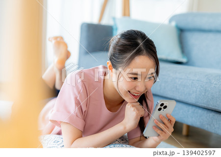 部屋でスマホを操作する若い女性 139402597