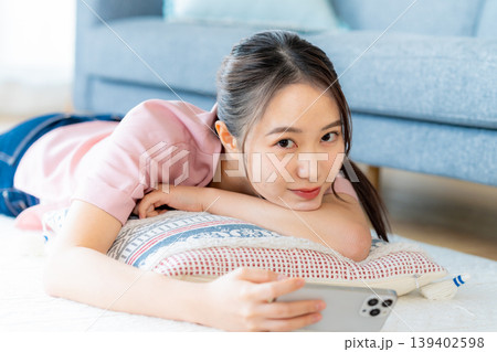 部屋でスマホを操作する若い女性 139402598