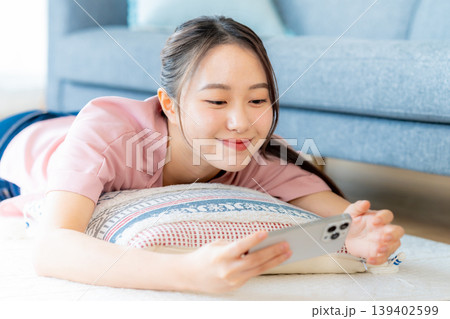 部屋でスマホを操作する若い女性 139402599