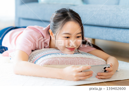 部屋でスマホを操作する若い女性 139402600