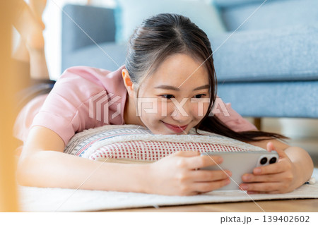 部屋でスマホを操作する若い女性 139402602