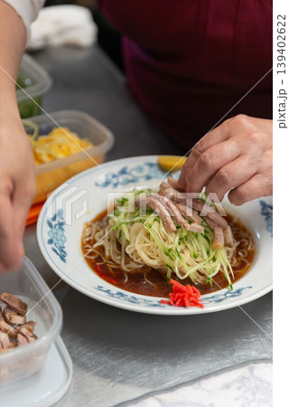 冷やし中華の麺の上にチャーシューを盛り付ける調理風景 139402622