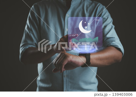 Man using smartwatch with sleep tracking hologram interface. Digital sleep quality monitor, insomnia analysis, and healthy night rest technology concept. 7 hours sleep cycle data. Man using smartwatch with sleep tracking hologram interface. Digital sleep quality monitor, insomnia analysis, and healthy night rest technology concept. 7 hours sleep cycle data. 139403006