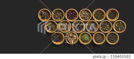 Elegant presentation of assorted dried herbs in textured wooden bowls with minimalistic background 139403503