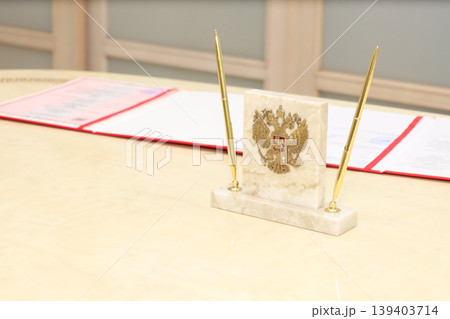 Golden pens stand beside a marble base with an emblem Golden pens stand beside a marble base with an emblem 139403714