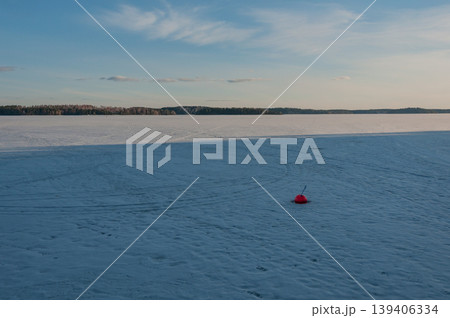 Lonely red buoy in frozen lake in Finland in springtime Lonely red buoy in frozen lake in Finland in springtime 139406334