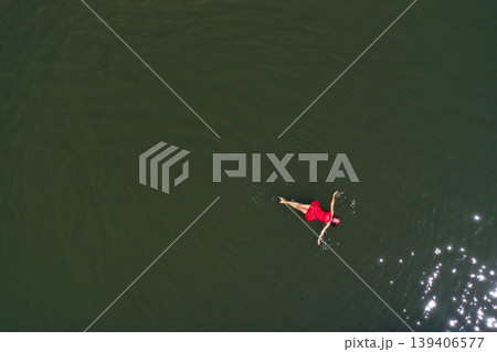 Aerial view of woman in red dress floats peacefully in a lake, embracing serenity and solitude Aerial view of woman in red dress floats peacefully in a lake, embracing serenity and solitude 139406577