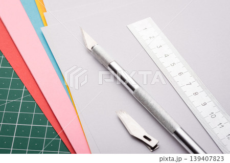 Professional scalpel, ruler and set of sharp blades on papers of different colour on cutting mat Professional scalpel, ruler and set of sharp blades on papers of different colour on cutting mat 139407823