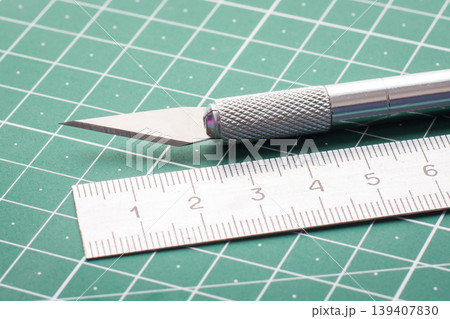 Close up photo of metal knife and ruler on cutting mat Close up photo of metal knife and ruler on cutting mat 139407830