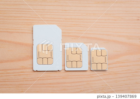SIM cards of different side on a wooden background. SIM card, micro SIM and nano SIM on table SIM cards of different side on a wooden background. SIM card, micro SIM and nano SIM on table 139407869