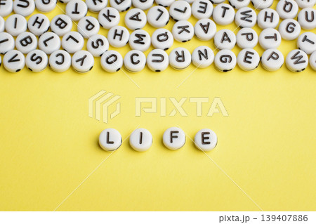 The word LIFE made of white plastic blocks on yellow background with many letters on the top The word LIFE made of white plastic blocks on yellow background with many letters on the top 139407886