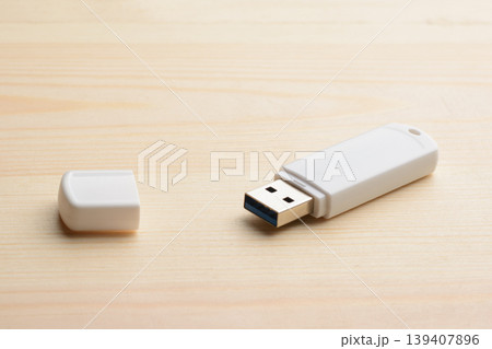 White USB stick with cap on a light wooden table 139407896