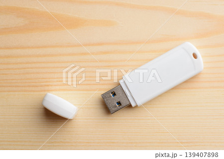 White USB stick with cap on a light wooden table 139407898