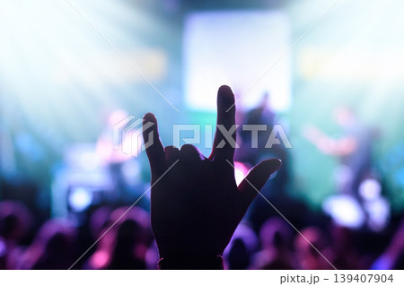 Silhouette of a male hand showing rock gesture against blurred stage with rock players during performance 139407904