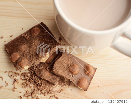 Cocoa in cup near broken bar of milk chocolate with nuts 139407912