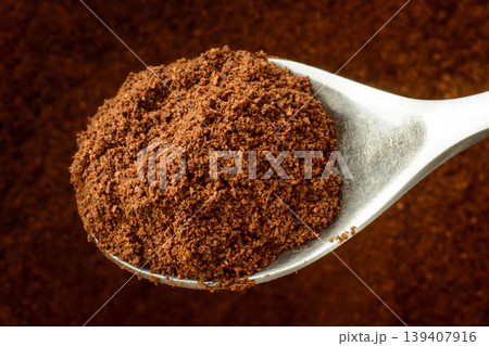 Spoon with some ground coffee against a coffee background 139407916