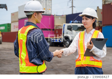 Asian male and female industrial supervisors shanking hands and concluding a successful business agreement and cargo inspection at a container terminal 139408427