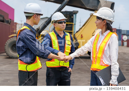 Diverse mid-adult Asian shipping workers stack hands in a show of partnership and unity at a Thai logistics yard 139408431