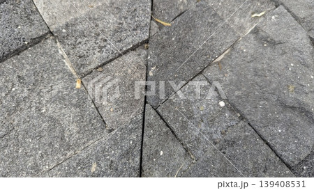 Detailed top view shows dark grey stone tiles with irregular triangular shapes. Textured volcanic rock surfaces create geometric patterns. Perfect for architectural backgrounds, paving design. 139408531
