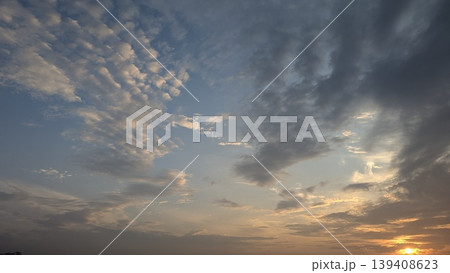 Wide shot shows blue sky, soft sunrise clouds. Golden light illuminates white, grey cloud patterns. Serene atmosphere for nature backgrounds, spiritual themes, weather concepts, peaceful designs. Wide shot shows blue sky, soft sunrise clouds. Golden light illuminates white, grey cloud patterns. Serene atmosphere for nature backgrounds, spiritual themes, weather concepts, peaceful designs. 139408623