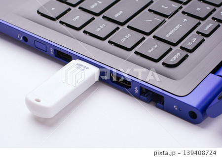 White USB stick plugged in the USB port of the modern blue laptop on a white table 139408724