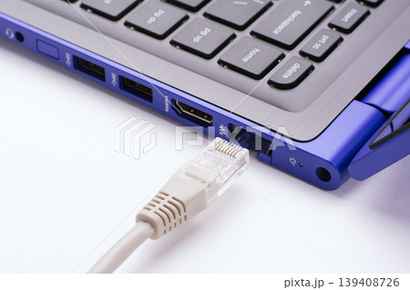 White LAN Internet cable near the port of a modern blue laptop White LAN Internet cable near the port of a modern blue laptop 139408726