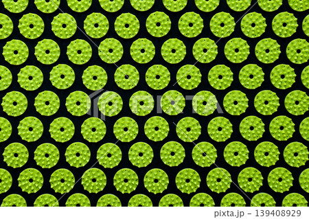 Abstract background of green acupressure massage mat spikes on a black fabric base 139408929