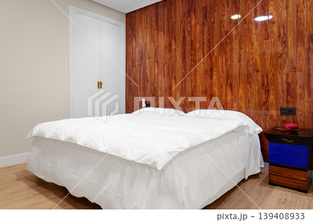 Modern budget hotel room interior with wooden accent wall and double bed. Concept of compact apartment rental 139408933