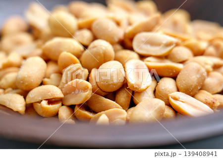Close view of roasted salted peanuts in wooden bowl. Golden kernels with sea salt crystals Close view of roasted salted peanuts in wooden bowl. Golden kernels with sea salt crystals 139408941