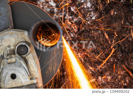 Close-up of an angle grinder cutting a steel pipe, producing bright orange sparks Close-up of an angle grinder cutting a steel pipe, producing bright orange sparks 139409202