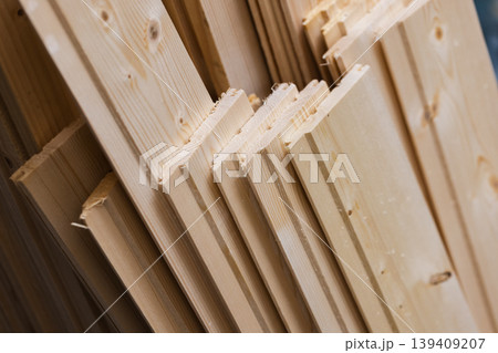 Stacked tongue-and-groove pine planks neatly arranged in a workshop 139409207