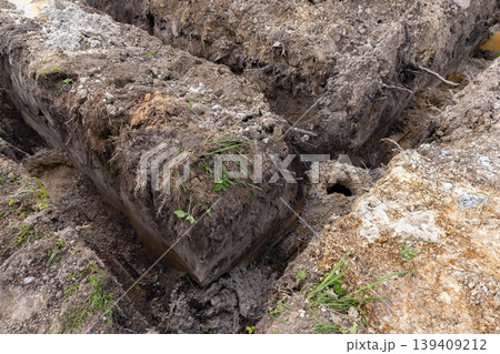 Excavated trenches with lifted sod blocks and exposed roots at a construction site 139409212